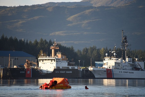Water survival training in Women's Bay, Kodiak Alaska. Two Coast Guard boats in harbor, mountains in background