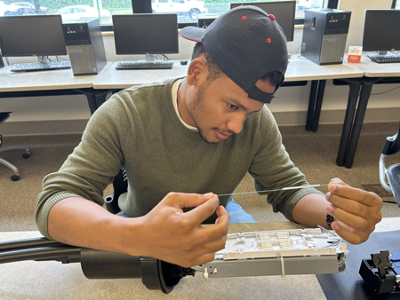Maine Kid learning how to splice A teenager in a computer class stares at fiber strand about fiber splice case