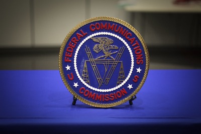 An embroidered patch of the FCC logo sits on a blue table