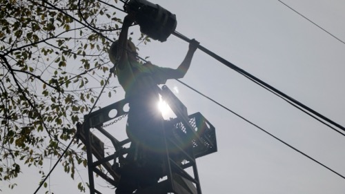 Vermont Utility worker attaches fiber near tree A utility worker is attaching a fiber line lifted into air by ladder truck near a tree branch