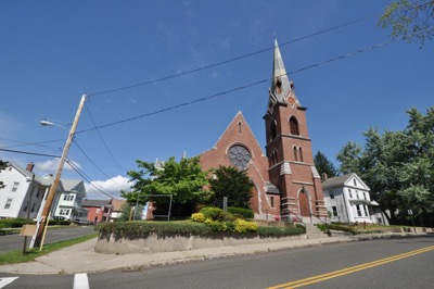 A brick church on the corner of a street in Chicopee MA with power lines over head