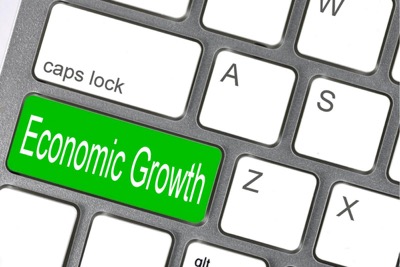 A computer keyboard shows a green button that reads: "economic growth"