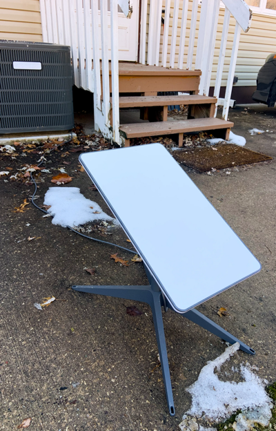 A starlink is positioned in the front yard of a home aimed at Starlink satellite