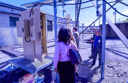 Three state officials look at DigitalC wireless equipment on a tour outside installation