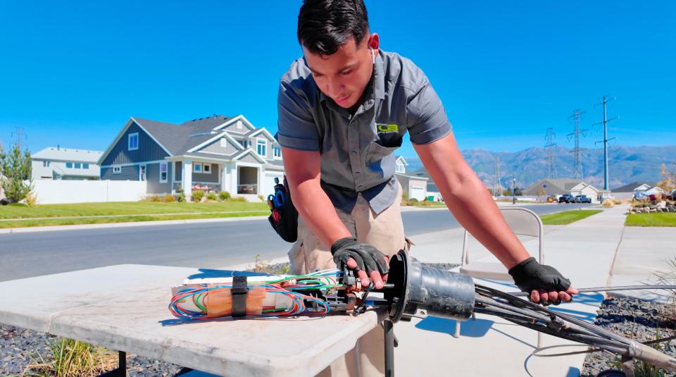 A fiber technician lays bare the insides of a fiber splice case in a residential neighborhood