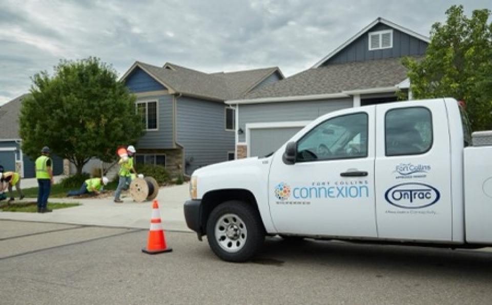 A Fort Collins Connexion truck is parked in front of home as three city employees install fiber near the driveway