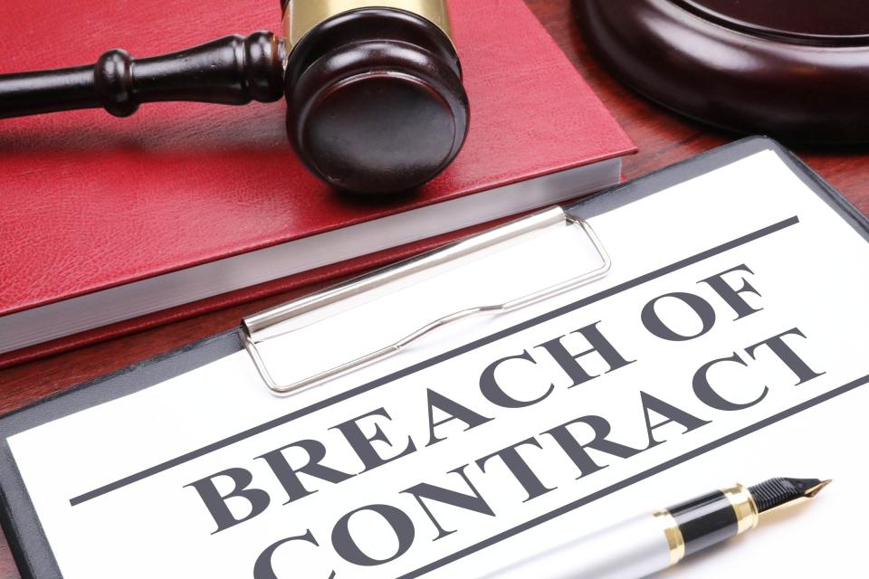 Breach of contract paperwork on desk next to a gavel