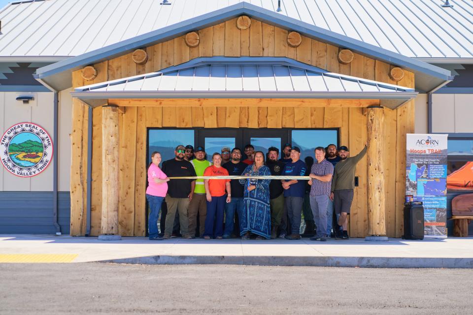 A dozen Hoopa Valley Tribe members holding ribbon up before cutting it at data center opening ceremony